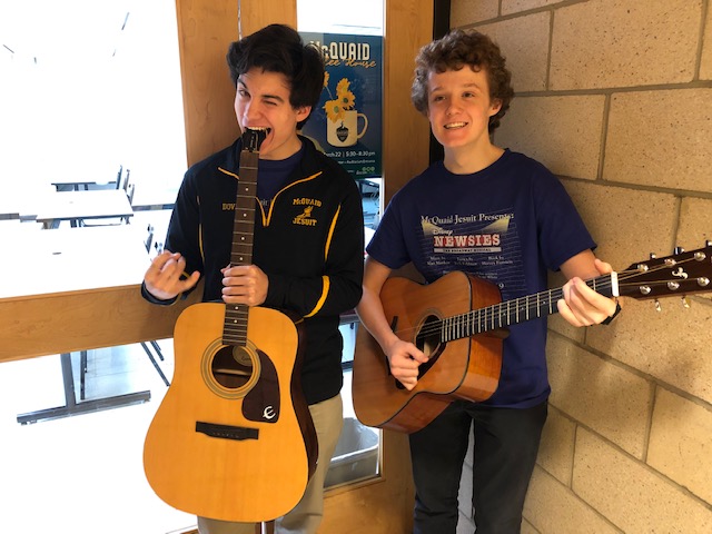 Juniors Tom Crowley and Spencer Dovi pose in front of the official 2019 McQuaid Coffee House poster wielding their instruments of choice.