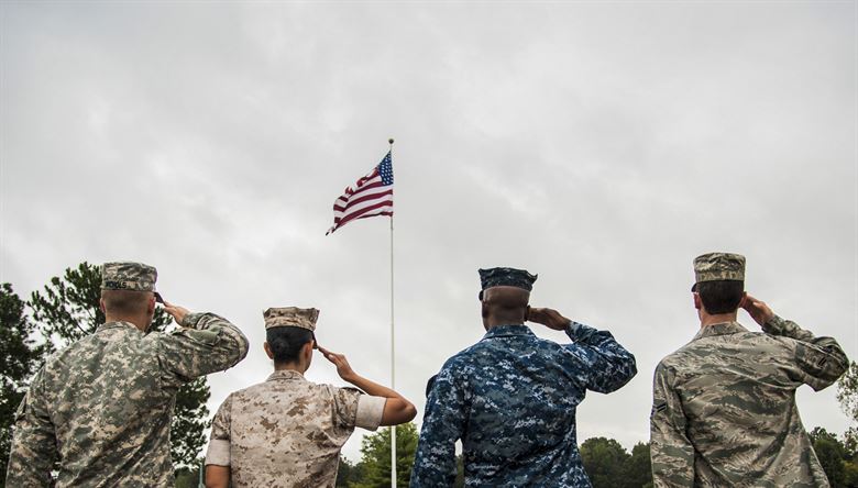 Servicemen and women of various branches salute our flag.