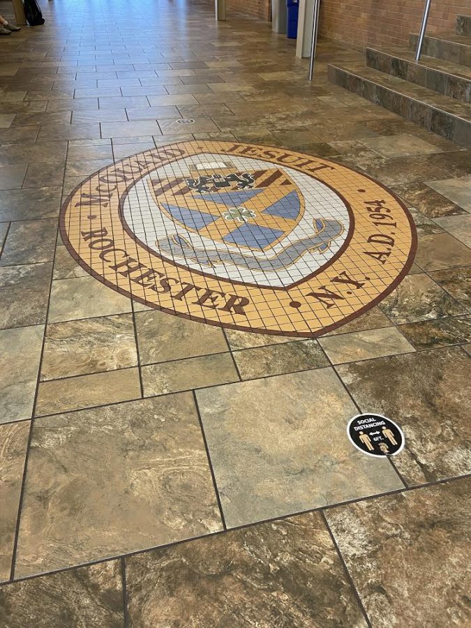 The McQuaid Jesuit emblem on the floor in Keenan Hall. This emblem serves as a reminder to McQuaid volleyball players of the pride and loyalty dedicated to the school.